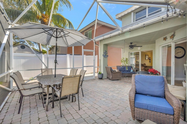 view of patio with an outdoor living space, ceiling fan, and glass enclosure