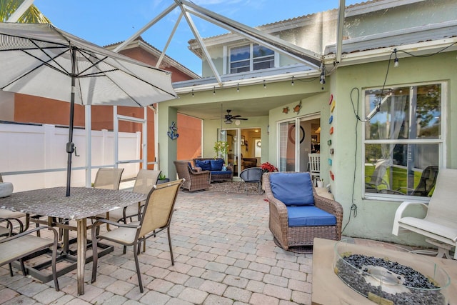 view of patio / terrace with ceiling fan and an outdoor living space with a fire pit