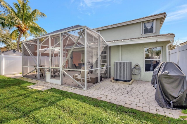 back of house featuring a patio, central AC, glass enclosure, and a lawn