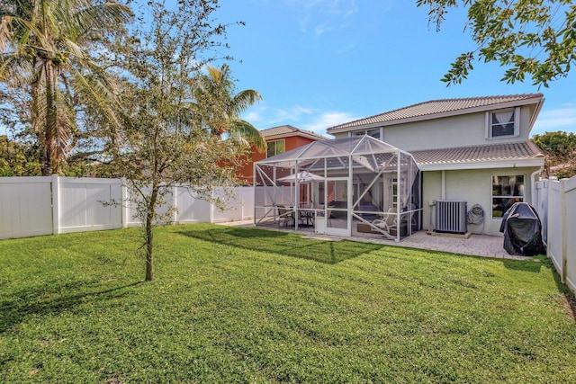 back of house with a yard, cooling unit, glass enclosure, and a patio area