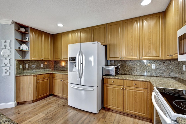 kitchen featuring a textured ceiling, backsplash, white appliances, and light hardwood / wood-style flooring