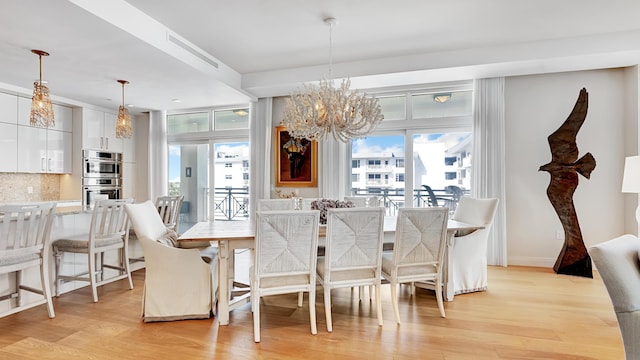 dining room with light hardwood / wood-style flooring and a chandelier