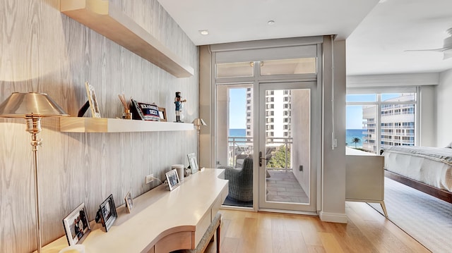 entryway with light hardwood / wood-style floors, ceiling fan, and a water view