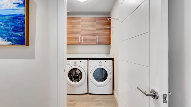 washroom featuring cabinets, independent washer and dryer, and light hardwood / wood-style flooring