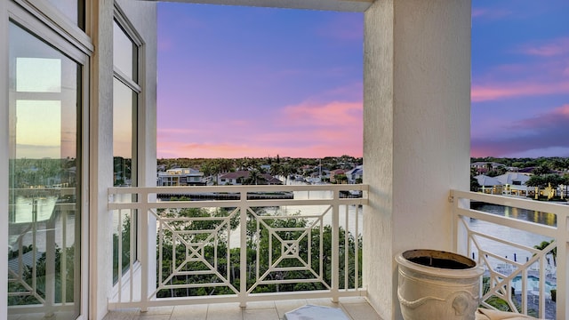 balcony at dusk featuring a water view