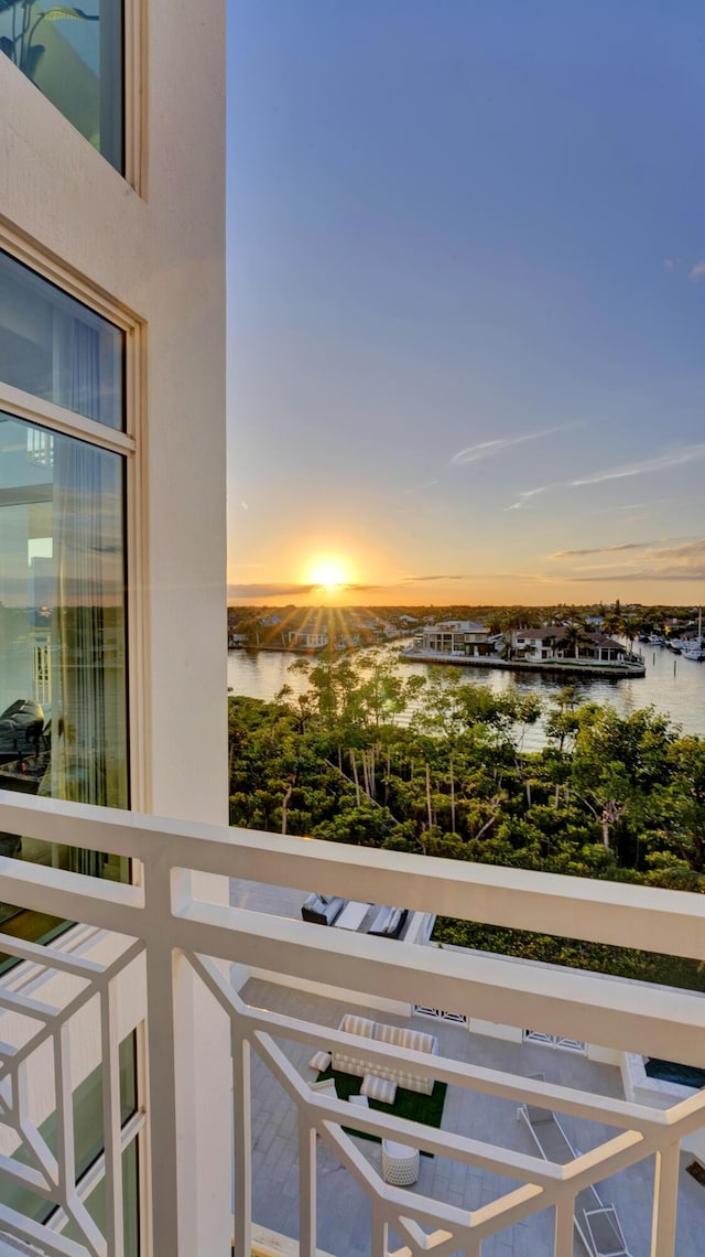 balcony at dusk featuring a water view