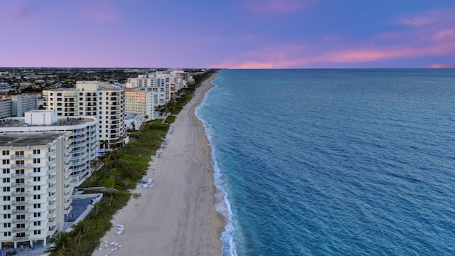 aerial view at dusk with a view of the beach and a water view