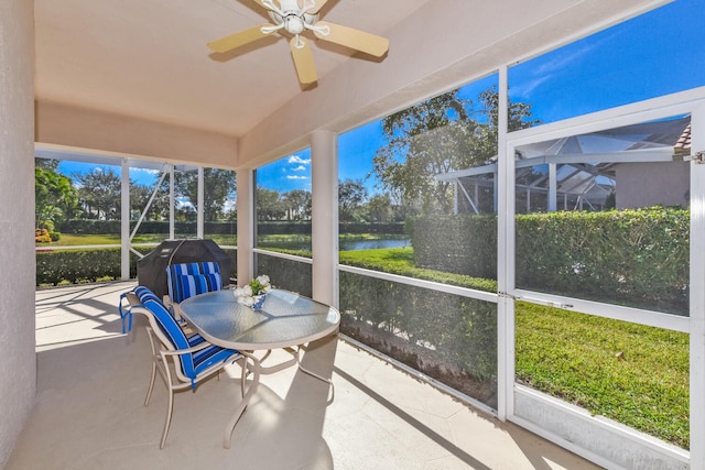 sunroom featuring a water view and ceiling fan