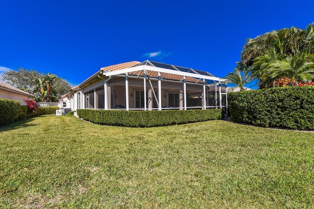 rear view of property with a lanai and a lawn