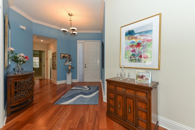 foyer entrance with an inviting chandelier, wood-type flooring, and ornamental molding