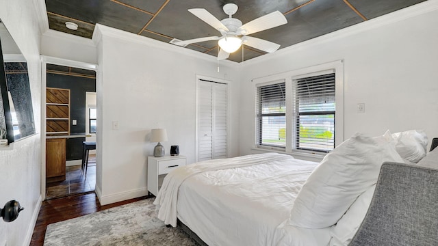 bedroom featuring dark wood-type flooring, ornamental molding, a closet, and ceiling fan