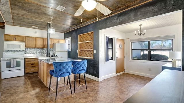 kitchen with a breakfast bar, pendant lighting, tasteful backsplash, an island with sink, and white appliances