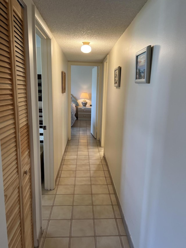 hallway featuring light tile patterned floors and a textured ceiling