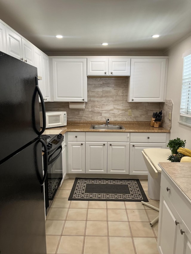 kitchen with sink, white cabinetry, range, black refrigerator, and backsplash