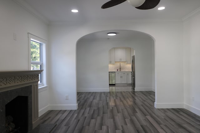 unfurnished living room featuring crown molding, dark hardwood / wood-style floors, ceiling fan, and a high end fireplace