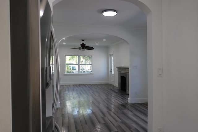 unfurnished living room with dark wood-type flooring, ornamental molding, and ceiling fan