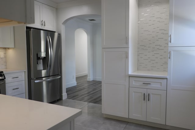 kitchen featuring white cabinetry, stainless steel fridge with ice dispenser, tasteful backsplash, and ornamental molding