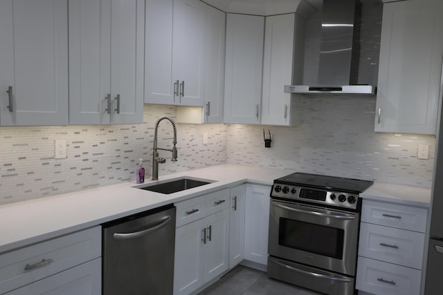 kitchen with sink, stainless steel appliances, white cabinets, decorative backsplash, and wall chimney exhaust hood