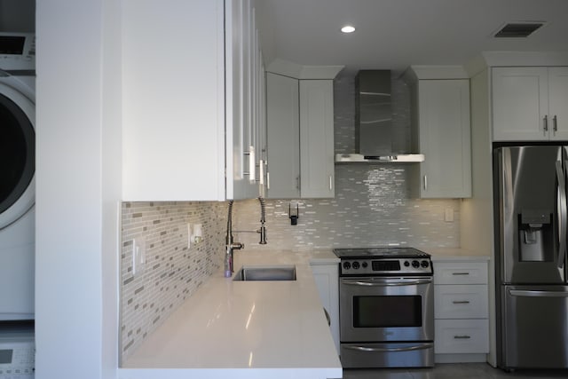 kitchen with wall chimney range hood, sink, white cabinets, and appliances with stainless steel finishes