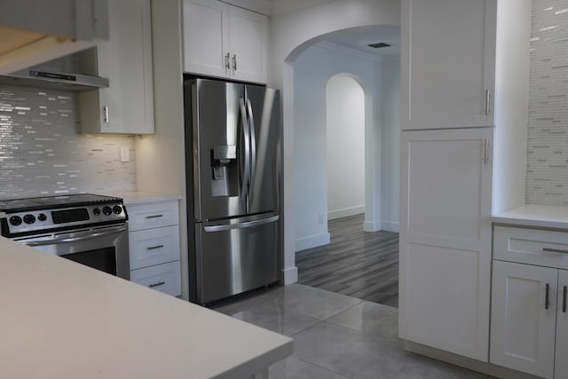 kitchen featuring crown molding, white cabinetry, stainless steel appliances, decorative backsplash, and wall chimney exhaust hood