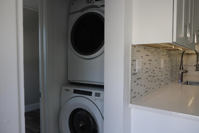 clothes washing area featuring stacked washer / drying machine and sink