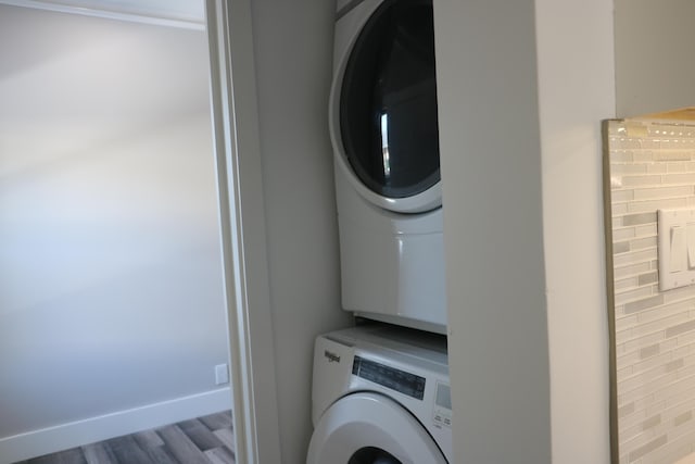 laundry area with stacked washing maching and dryer and light hardwood / wood-style floors