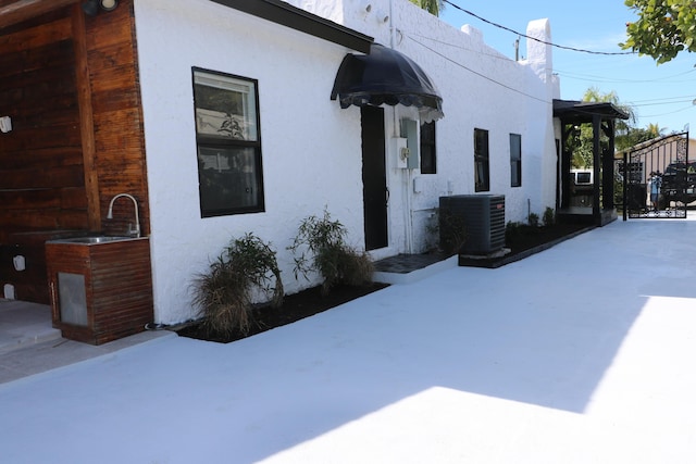 view of side of property featuring sink and central air condition unit