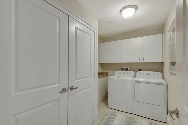 laundry area with cabinets, a textured ceiling, and washer and clothes dryer