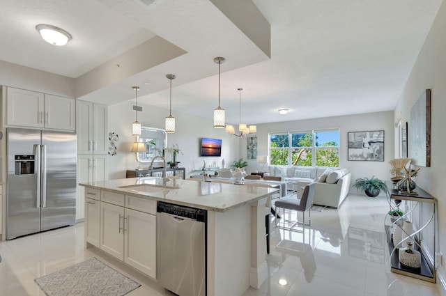 kitchen featuring sink, stainless steel appliances, white cabinets, and a center island with sink