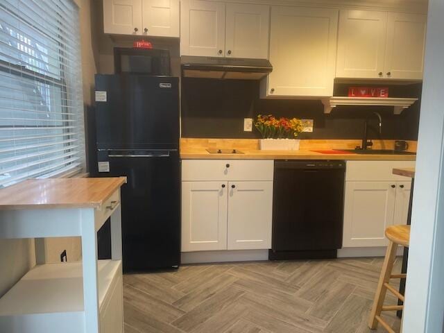 kitchen featuring white cabinetry, light parquet flooring, butcher block countertops, and black appliances