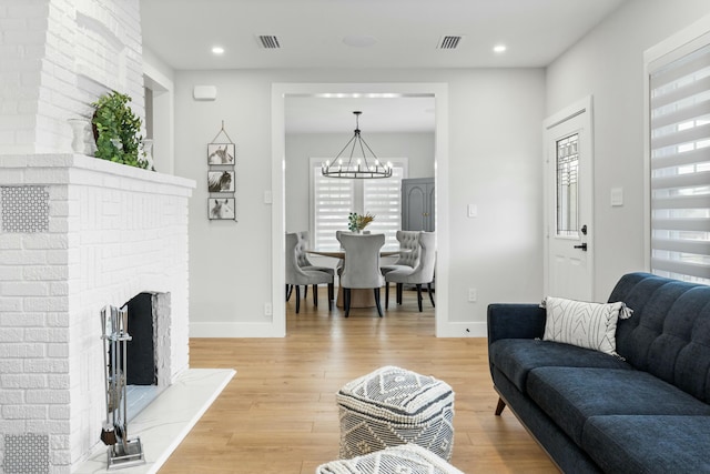 living room with an inviting chandelier, wood-type flooring, a fireplace, and plenty of natural light