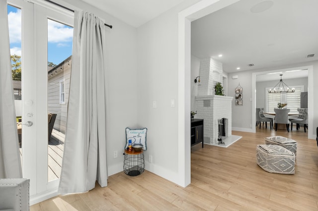 entryway with hardwood / wood-style flooring, a fireplace, and a notable chandelier