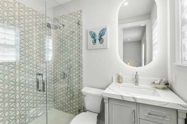 bathroom with vanity, toilet, and a tile shower