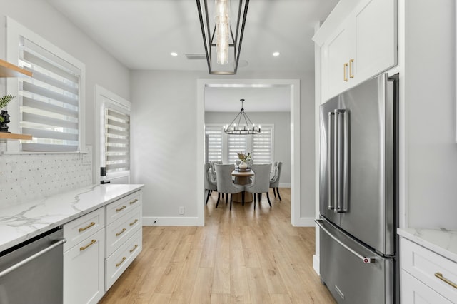 kitchen with light stone counters, stainless steel appliances, hanging light fixtures, and white cabinets