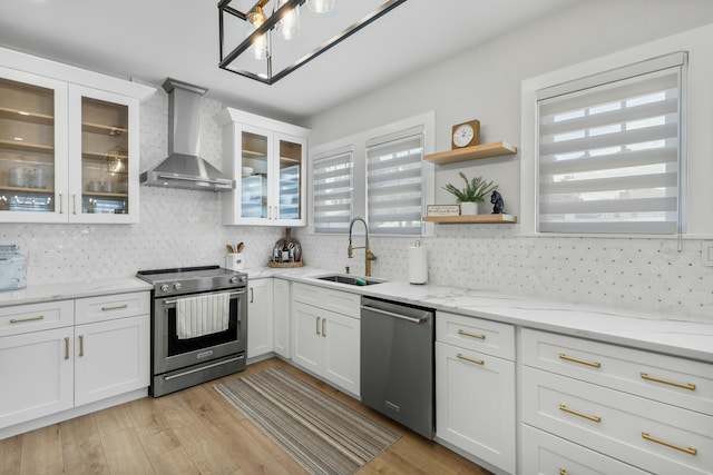 kitchen with stainless steel appliances, sink, white cabinets, and wall chimney exhaust hood