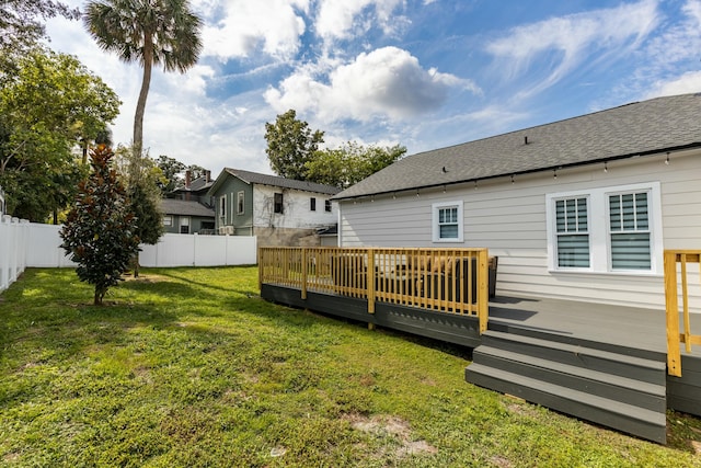 rear view of property with a wooden deck and a lawn