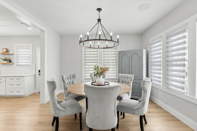 dining room with a notable chandelier, a healthy amount of sunlight, and light wood-type flooring