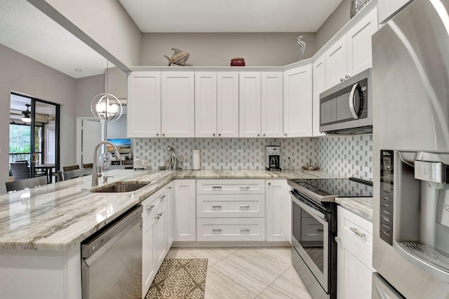 kitchen with sink, white cabinetry, hanging light fixtures, stainless steel appliances, and light stone countertops