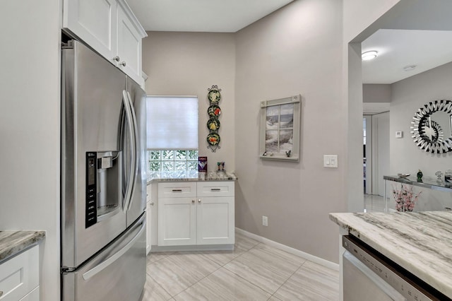 kitchen featuring appliances with stainless steel finishes, white cabinets, and light stone counters