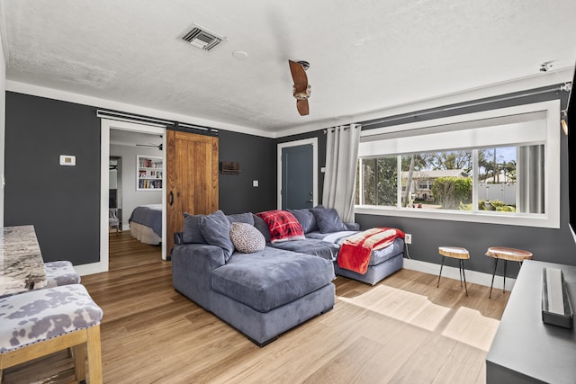 living room featuring a barn door, a textured ceiling, and light hardwood / wood-style floors