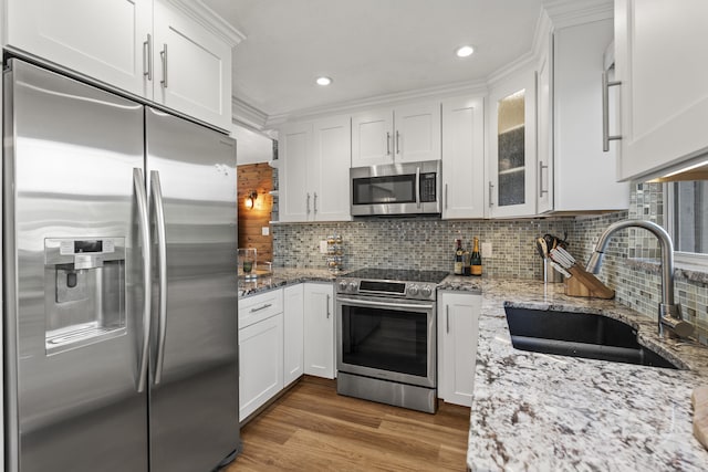 kitchen featuring sink, stainless steel appliances, light stone counters, white cabinets, and decorative backsplash