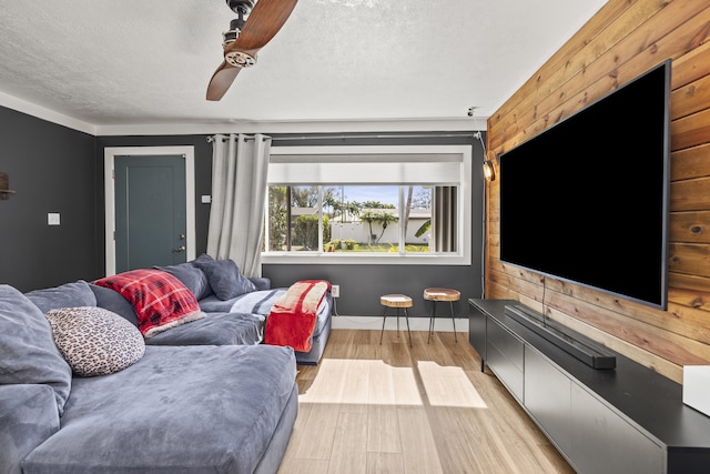 living room with ceiling fan, a textured ceiling, and light hardwood / wood-style flooring