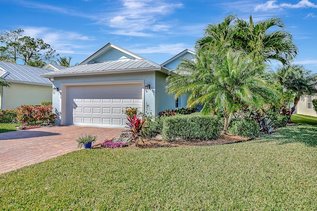 single story home with a garage, metal roof, decorative driveway, a front lawn, and stucco siding