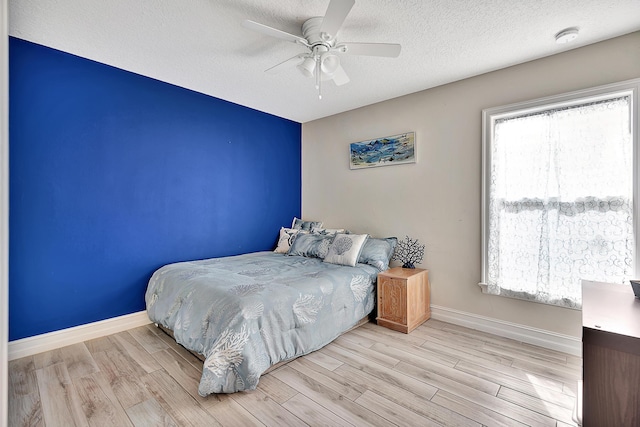 bedroom featuring ceiling fan, light hardwood / wood-style flooring, and a textured ceiling