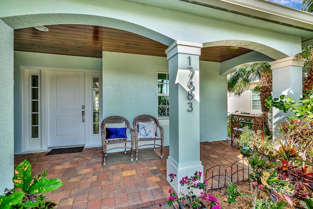 view of exterior entry with a porch and stucco siding