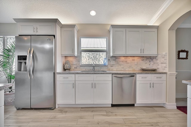 kitchen featuring sink, stainless steel appliances, white cabinets, and light stone countertops