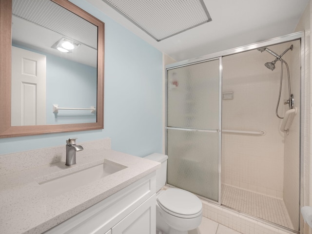 bathroom featuring tile patterned flooring, vanity, a shower with shower door, and toilet