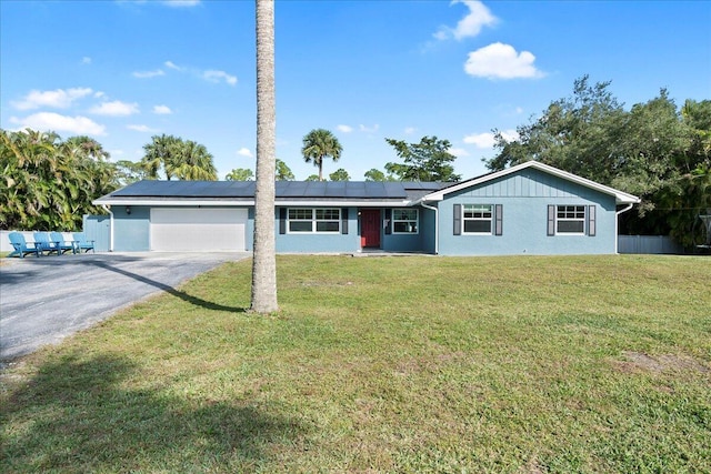 ranch-style house with a garage, a front lawn, and solar panels