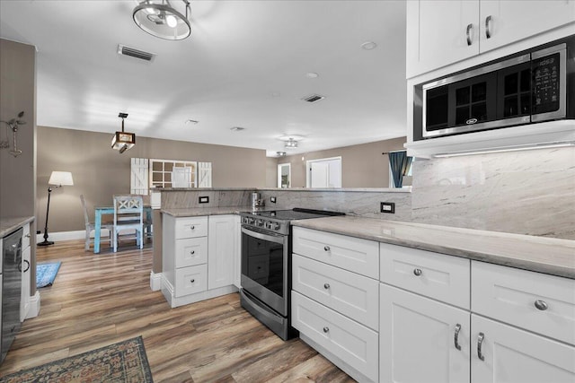 kitchen with pendant lighting, stainless steel appliances, kitchen peninsula, and white cabinets