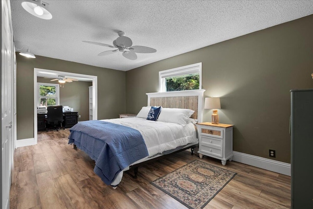 bedroom with ceiling fan, hardwood / wood-style floors, and a textured ceiling